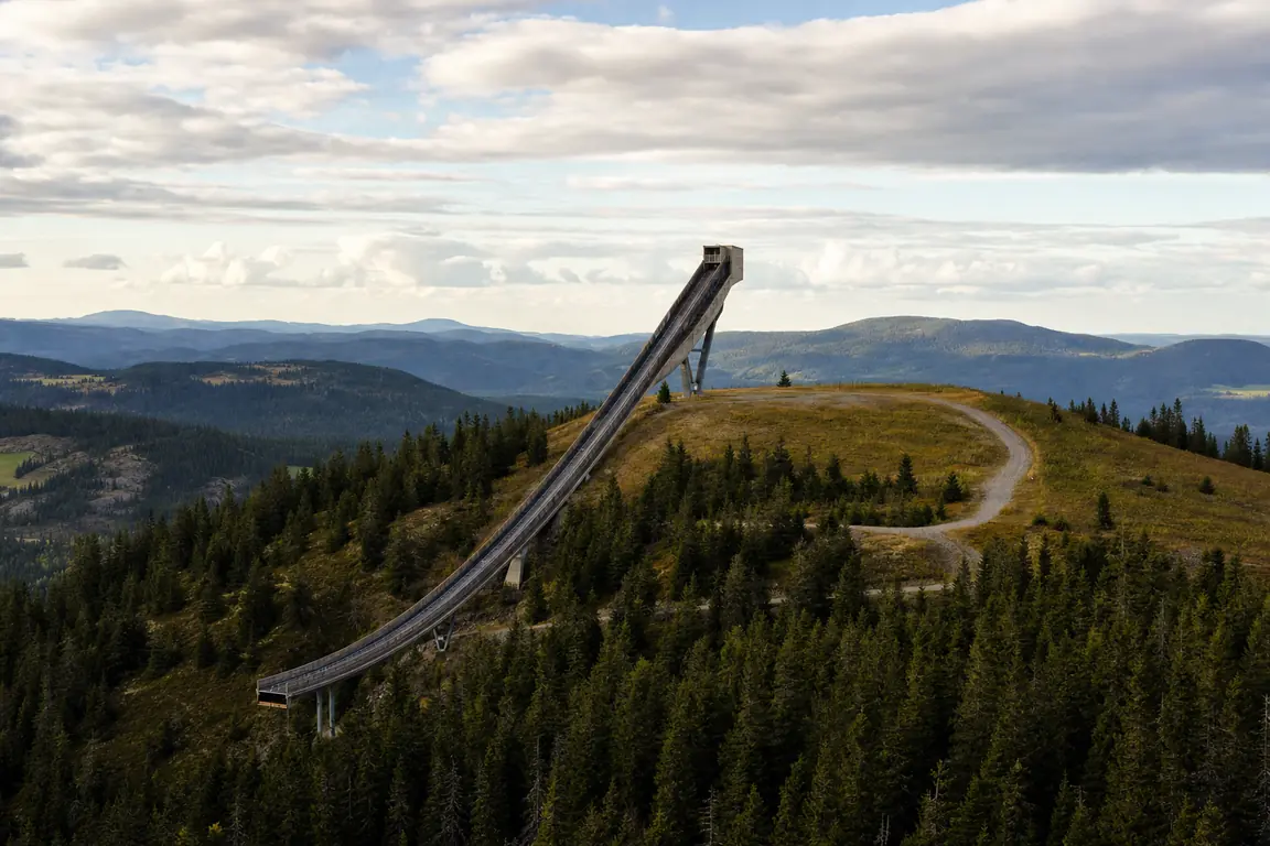 Große Stahlsprungschanze auf einem bewaldeten Gipfel mit langer Anlaufbahn