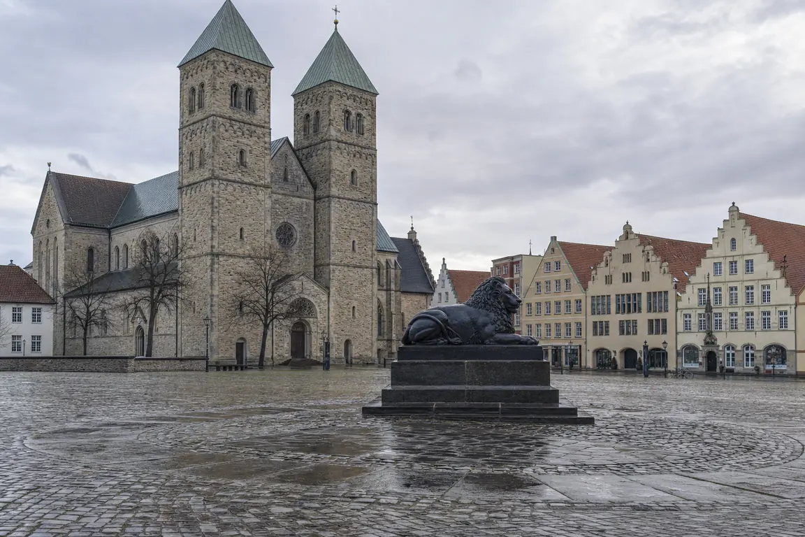 Weiter gepflasterter Stadtplatz mit romanischem Dom und bronzenem Löwenstandbild