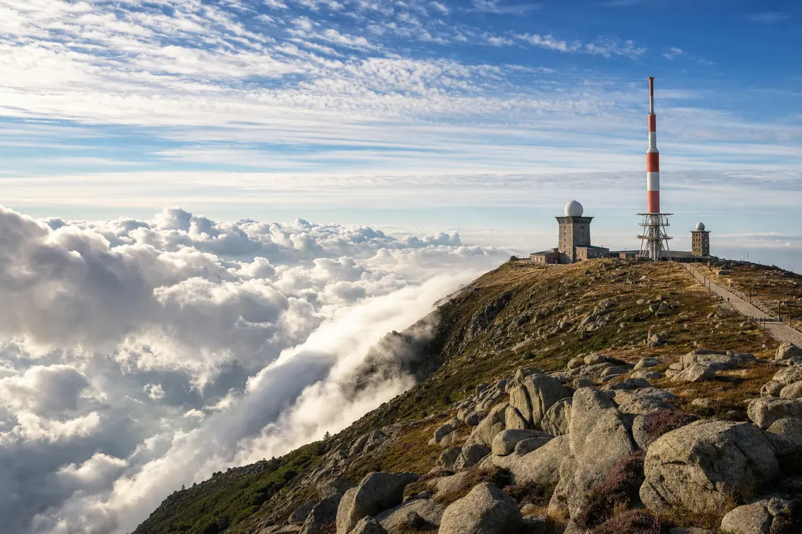 Der Gipfel des Brockens mit Sendeturm und Brockenhaus über einer Wolkendecke