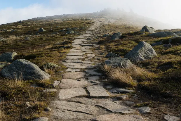 Steinplattenweg über das offene Plateau zum Gipfelgrat