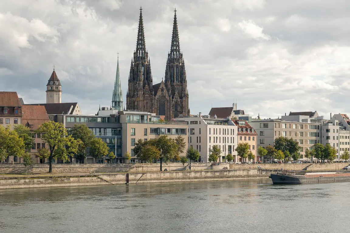 Flussufer mit steinerner Uferpromenade und gotischem Dom mit zwei Türmen dahinter